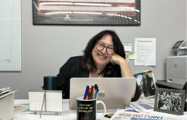 WORKING: Mrs. Keene perched at her desk in the Boiling Point office. She keeps a photo of her father with Reverend Dr. Martin Luther King Jr. (at right) for inspiration, as well as mugs with slogans and various newspapers.